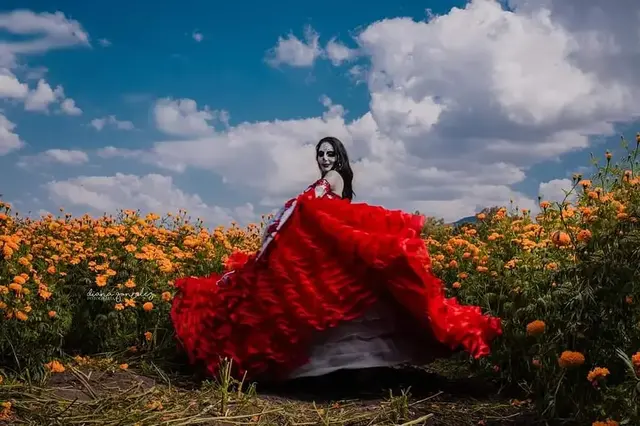 Catrina con vestido rojo entre flores de cempasúchil
